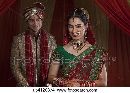 Picture - Portrait of newly married woman with husband in the background . Fotosearch