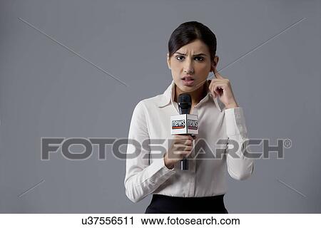 Stock Image - Portrait of news reporter listening against colored background . Fotosearch