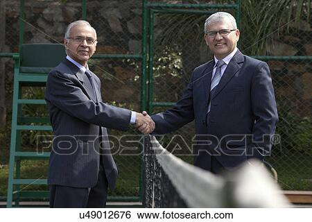 Portrait of senior male professionals shaking hands over tennis net in court View Large Photo Image Stock Photograph - Portrait of senior male professionals shaking hands over tennis net in court . Fotosearch