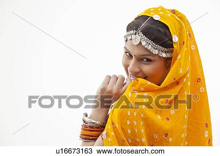 Stock Image - Portrait of shy woman in traditional clothing looking over shoulder against white background. Fotosearch
