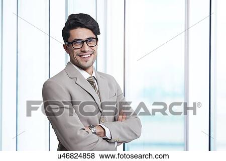 Portrait of smiling businessman standing arms crossed in office View Large Photo Image Stock Photo - Portrait of smiling businessman standing arms crossed in office. Fotosearch
