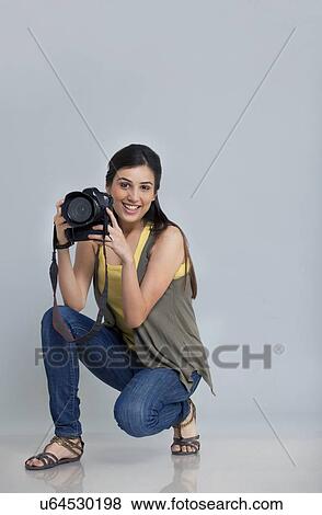 Stock Photo - Portrait of smiling female photographer with camera in her studio . Fotosearch