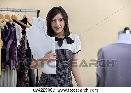 Stock Photo - Portrait of smiling young fashion designer standing in store . Fotosearch