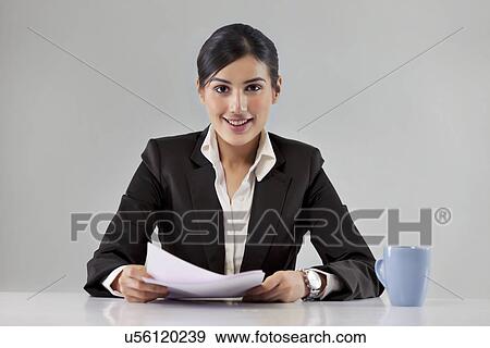 Stock Photo - Portrait of smiling young news television host with coffee cup and paper . Fotosearch