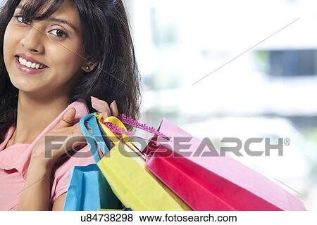 Portrait of smiling young woman carrying shopping bags View Large Photo Image Stock Photo - Portrait of smiling young woman carrying shopping bags . Fotosearch