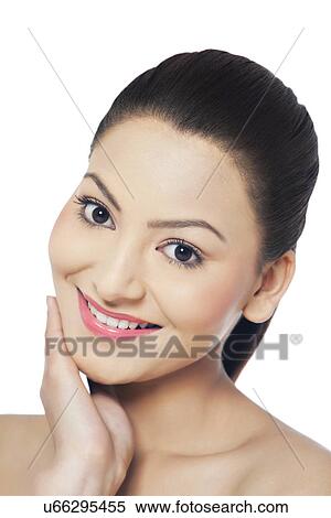 Stock Photography - Portrait of smiling young woman touching her face . Fotosearch