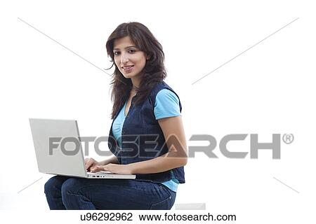 Portrait of smiling young woman using laptop against white background View Large Photo Image Stock Image - Portrait of smiling young woman using laptop against white background . Fotosearch