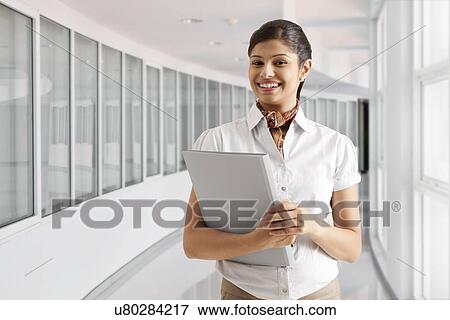 Stock Photo - Portrait of successful young businesswoman smiling with documents . Fotosearch