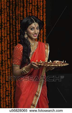 Stock Photography - Portrait of woman holding a tray of diyas. Fotosearch