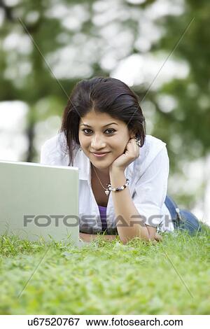 Portrait of woman lying on grass in lawn and using laptop View Large Photo Image Stock Photo - Portrait of woman lying on grass in lawn and using laptop . Fotosearch