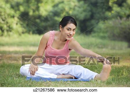 Stock Photograph - Portrait of woman on grass stretching . Fotosearch