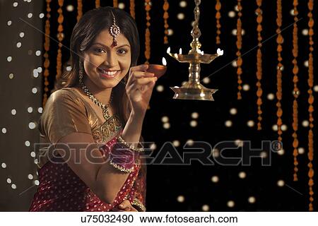 Stock Image - Portrait of woman with a diya . Fotosearch