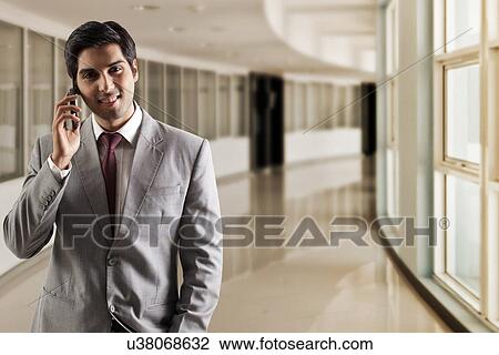 Stock Image - Portrait of young business man talking on phone . Fotosearch