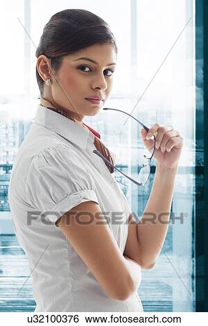 Stock Photograph - Portrait of young businesswoman holding glasses with pride . Fotosearch