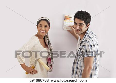 Stock Image - Portrait of young couple selecting color for their wall . Fotosearch