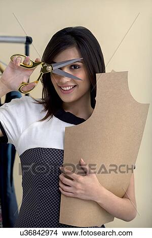 Portrait of young fashion designer holding scissors and cardboard View Large Photo Image Picture - Portrait of young fashion designer holding scissors and cardboard . Fotosearch
