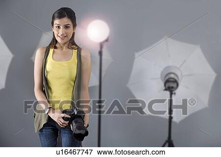 Portrait of young female photographer with camera standing in front of spotlight in studio View Large Photo Image Stock Photo - Portrait of young female photographer with camera standing in front of spotlight in studio . Fotosearch
