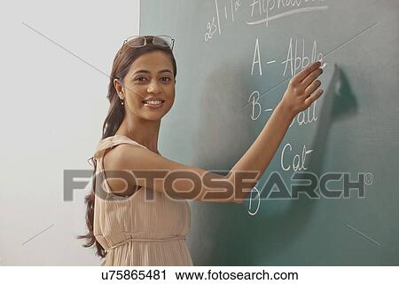 Portrait of young female teacher writing on green board View Large Photo Image Stock Image - Portrait of young female teacher writing on green board . Fotosearch