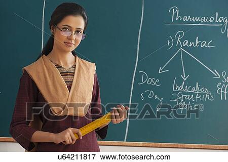 Portrait of young female teacher holding ruler against chalkboard View Large Photo Image Stock Photo - Portrait of young female teacher holding ruler against chalkboard . Fotosearch