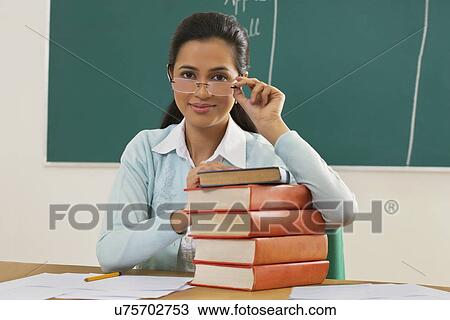 Portrait of young female teacher with stack of books at desk View Large Photo Image Stock Image - Portrait of young female teacher with stack of books at desk . Fotosearch