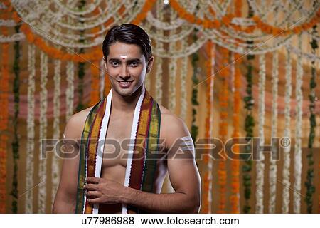 Stock Photo - Portrait of young groom with flower decoration in background . Fotosearch