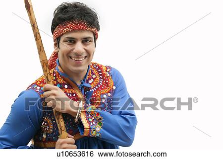 Portrait of young man in traditional wear holding stick against white background View Large Photo Image Stock Photograph - Portrait of young man in traditional wear holding stick against white background. Fotosearch