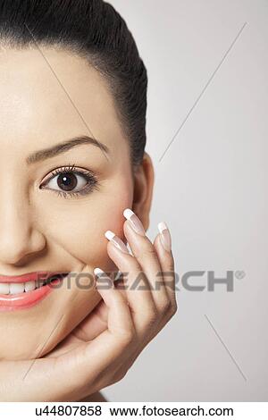 Portrait of young smiling woman with hand on chin over grey background View Large Photo Image Stock Photo - Portrait of young smiling woman with hand on chin over grey background . Fotosearch