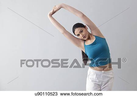 Portrait of young woman doing stretching exercise isolated over gray background View Large Photo Image Stock Image - Portrait of young woman doing stretching exercise isolated over gray background . Fotosearch