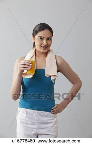 Portrait of young woman holding glass of orange juice against gray background View Large Photo Image Stock Image - Portrait of young woman holding glass of orange juice against gray background . Fotosearch