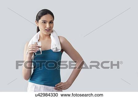 Portrait of young woman holding glass of water isolated over gray background View Large Photo Image Stock Image - Portrait of young woman holding glass of water isolated over gray background . Fotosearch