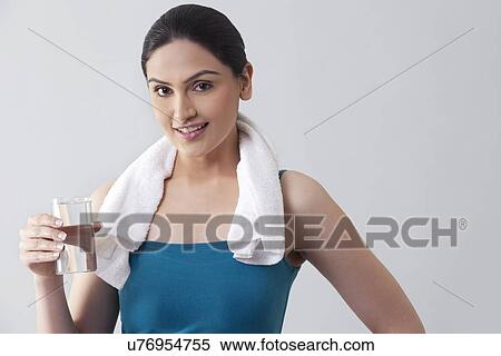 Portrait of young woman holding glass of water against gray background View Large Photo Image Stock Photography - Portrait of young woman holding glass of water against gray background . Fotosearch