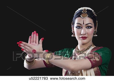 Stock Image - Portrait of young woman making Bharatanatyam gesture called Chakram on black background. Fotosearch