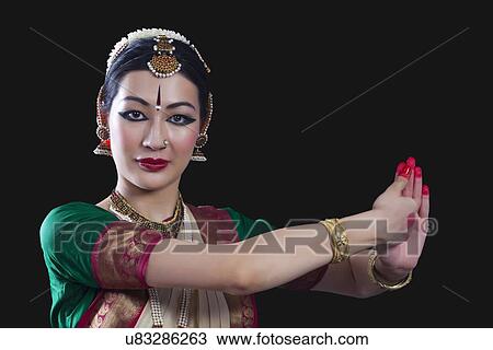 Stock Image - Portrait of young woman making Bharatanatyam gesture called Shankha on black background. Fotosearch