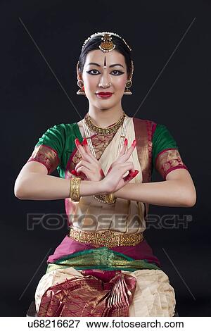 Stock Photo - Portrait of young woman making Bharatanatyam gesture called Kartari-Swastikam on black background. Fotosearch