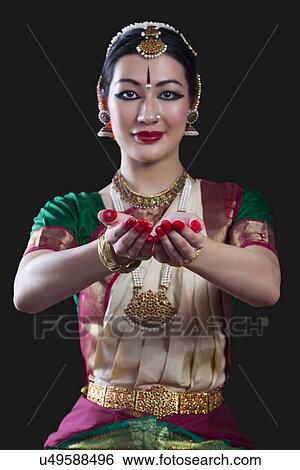 Stock Photograph - Portrait of young woman making Bharatanatyam gesture called Pushpaputam on black background. Fotosearch