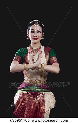 Stock Photography - Portrait of young woman making Bharatanatyam gesture called Swastikam on black background. Fotosearch