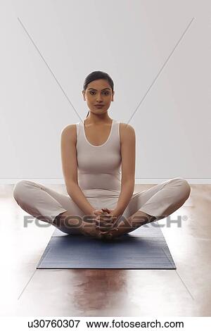 Portrait of young woman sitting in butterfly position on mat View Large Photo Image Stock Photo - Portrait of young woman sitting in butterfly position on mat. Fotosearch