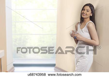 Portrait of young woman smiling while holding cup of herbal tea View Large Photo Image Stock Photo - Portrait of young woman smiling while holding cup of herbal tea . Fotosearch