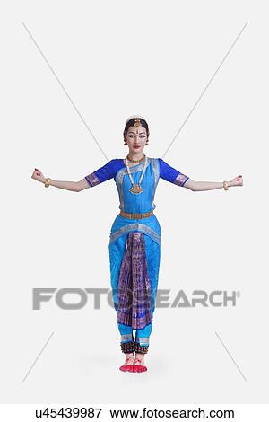 Stock Photo - Portrait of young woman with arms outstretched performing Bharatanatyam against white background. Fotosearch