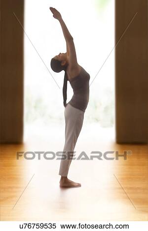 Stock Photography - Profile shot of young woman doing back bend yoga pose on hardwood floor. Fotosearch