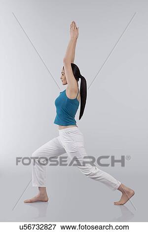 Stock Photo - Profile shot of young woman stretching arms upwards isolated over gray background. Fotosearch