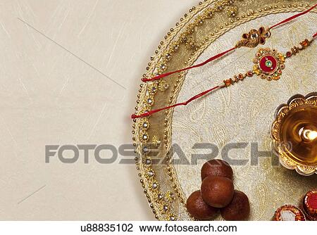 Stock Image - Rakhi, diya and sweets in a tray . Fotosearch