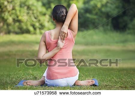 Stock Photo - Rear view of a woman stretching her arms in a yoga . Fotosearch