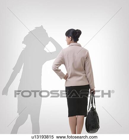 Rear view of businesswoman looking at her shadow dancing over gray background View Large Photo Image Stock Photography - Rear view of businesswoman looking at her shadow dancing over gray background. Fotosearch