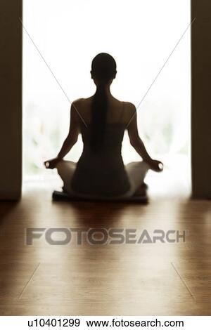 Stock Photo - Rear view of woman meditating on floor. Fotosearch