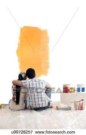 Stock Photo - Rear view of young couple looking at color sample together on the wall . Fotosearch