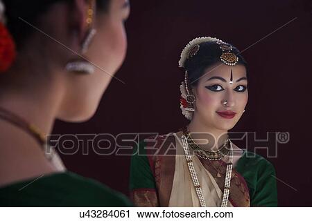 Stock Image - Reflection of beautiful Bharatanatyam dancer in mirror over black background. Fotosearch