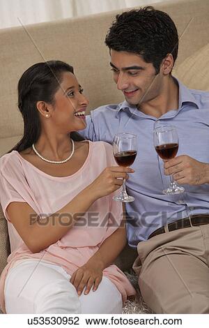 Stock Image - Relaxed young couple holding wineglass together at home . Fotosearch