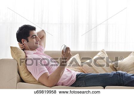 Stock Photo - Relaxed young man listening to music at home . Fotosearch