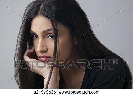 Sad Indian young woman looking away with hand on chin over colored background View Large Photo Image Stock Photography - Sad Indian young woman looking away with hand on chin over colored background . Fotosearch